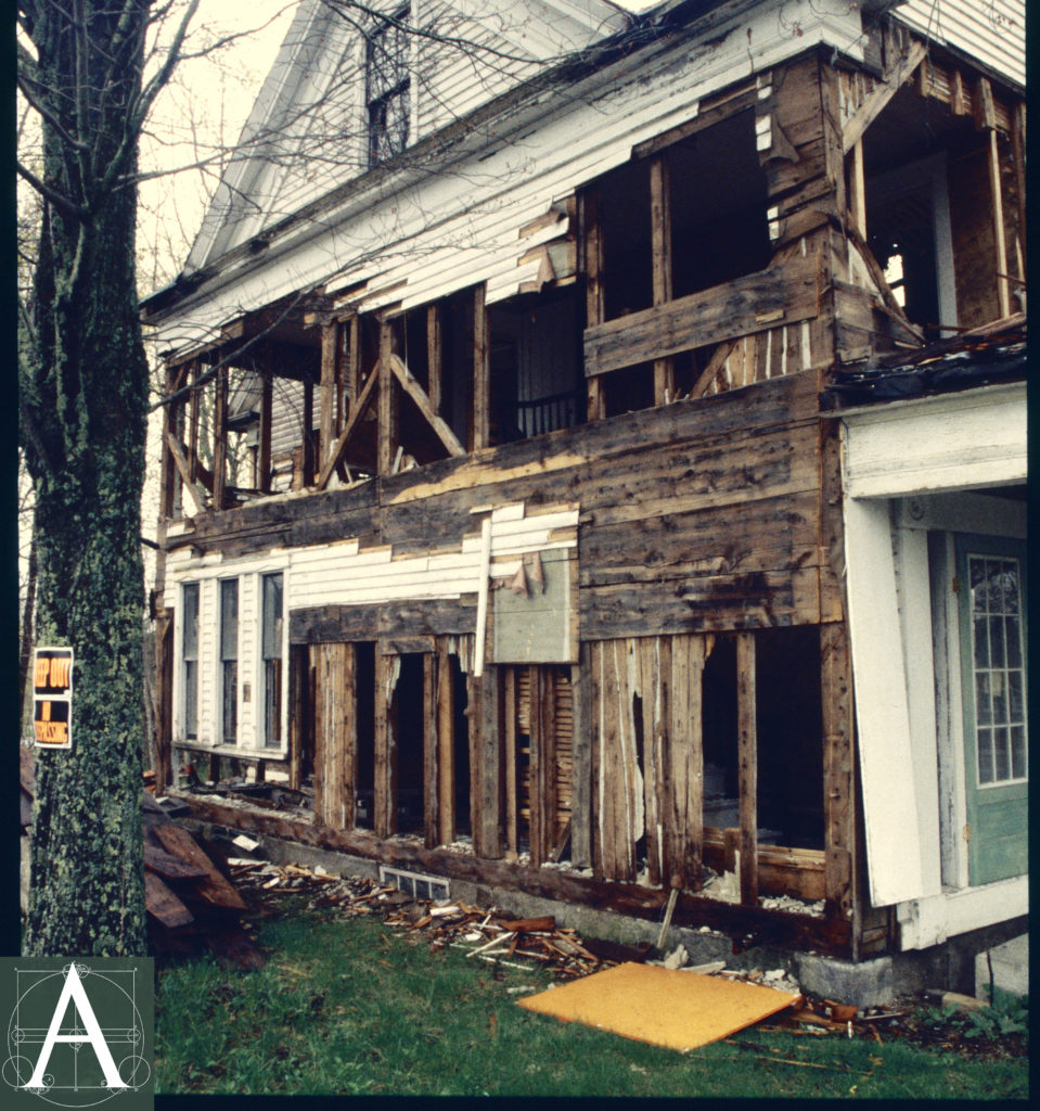 side (west) elevation showing partially stripped siding, timber frame and interior lath and plaster